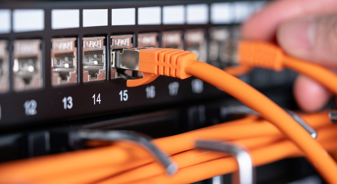 Patchpanel mit angeschlossenen orangefarbenen Netzwerkkabeln.