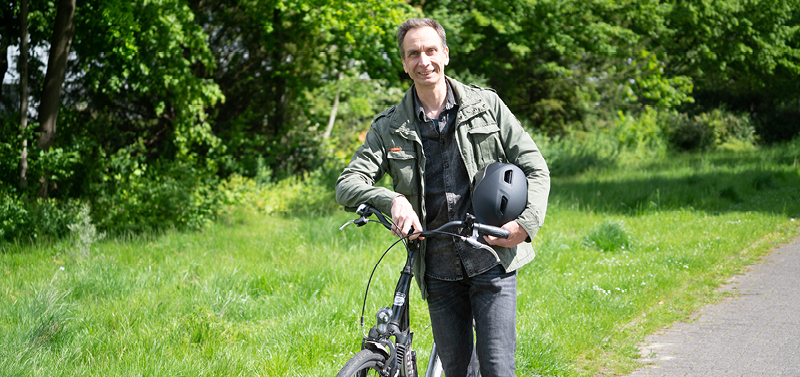 Ein Mann schiebt ein Fahrrad auf einem Radweg