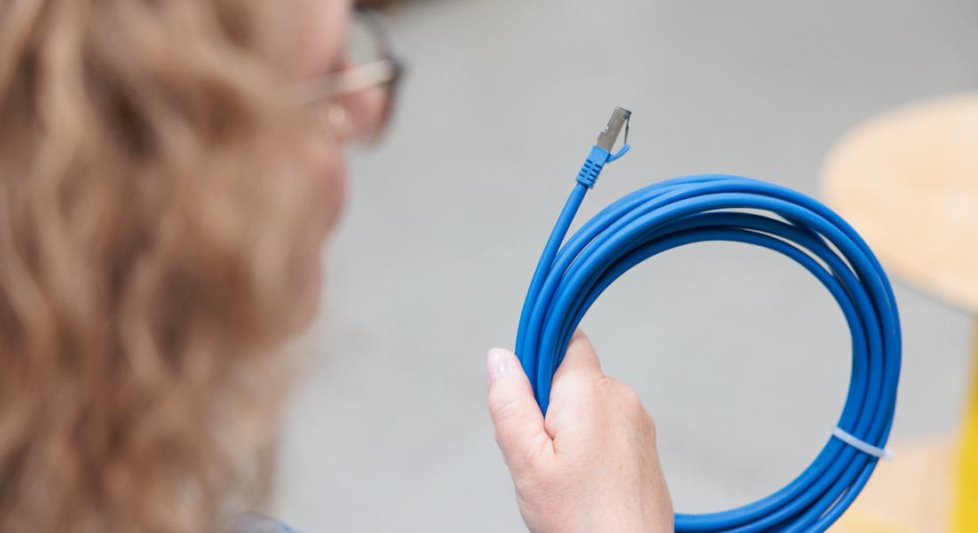 Woman holding blue network cable with RJ45 plug.