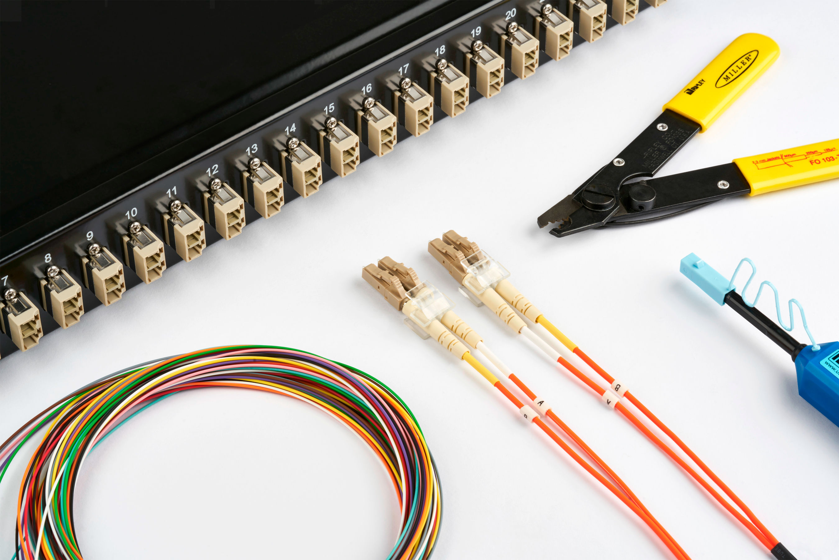 Netzwerkkomponenten und Werkzeuge, darunter ein Patchpanel, LWL-Patchkabel, farbige Kabel und ein Abisolierwerkzeug.