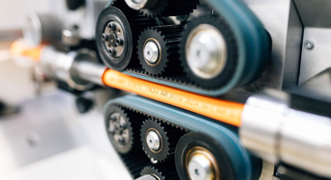 Close-up of a machine processing an orange cable.